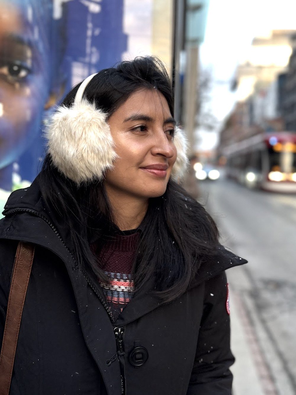 Retrato de Liseth Ruiz en una calle del centro de Toronto en invierno, con un tranvía de la TTC al fondo